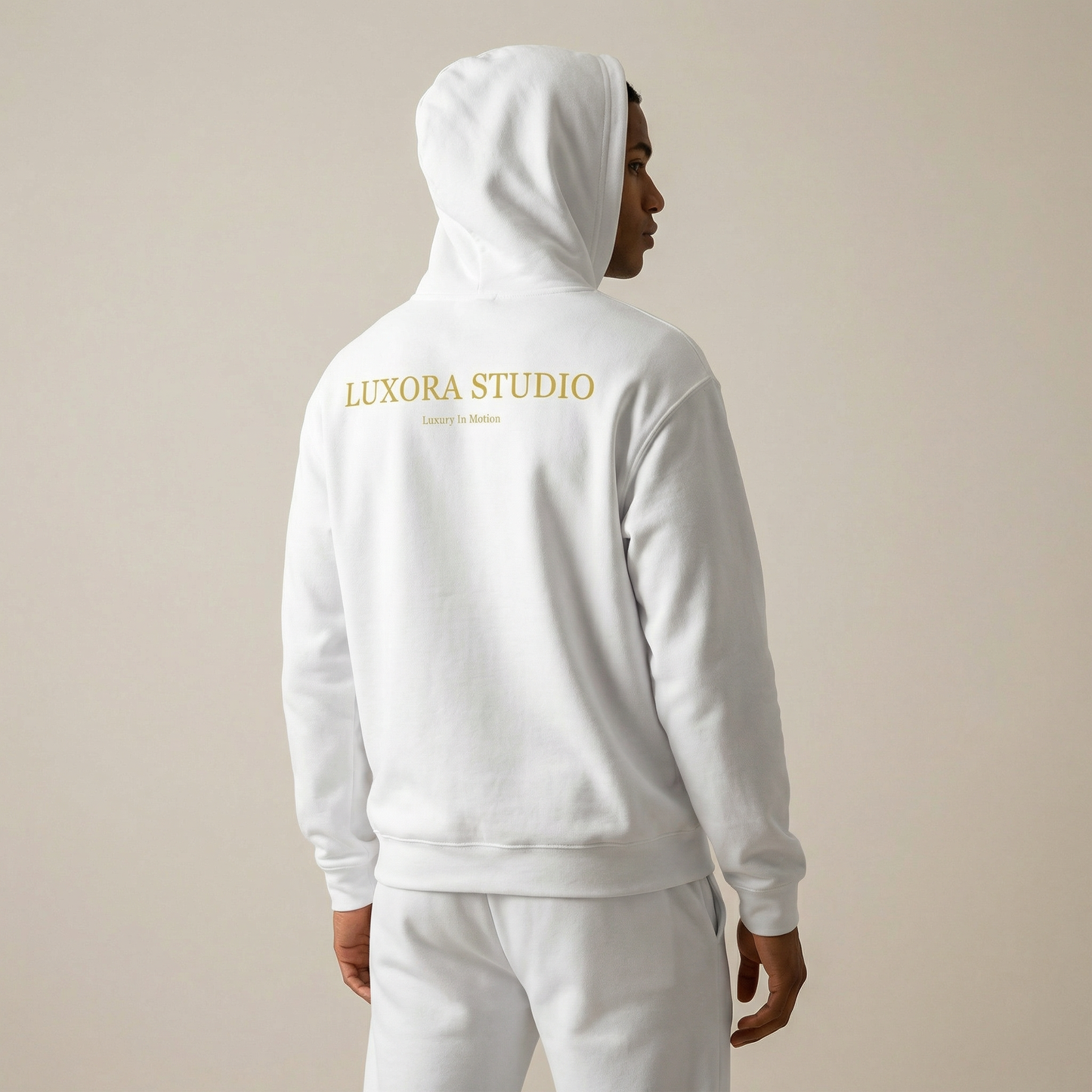 Person wearing a white hoodie with 'Luxora Studio' branding on the back against a beige background