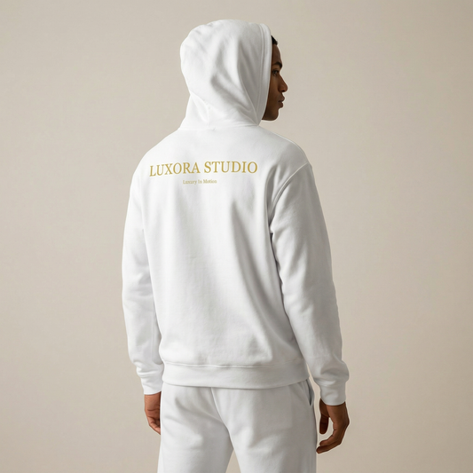 Person wearing a white hoodie with 'Luxora Studio' branding on the back against a beige background
